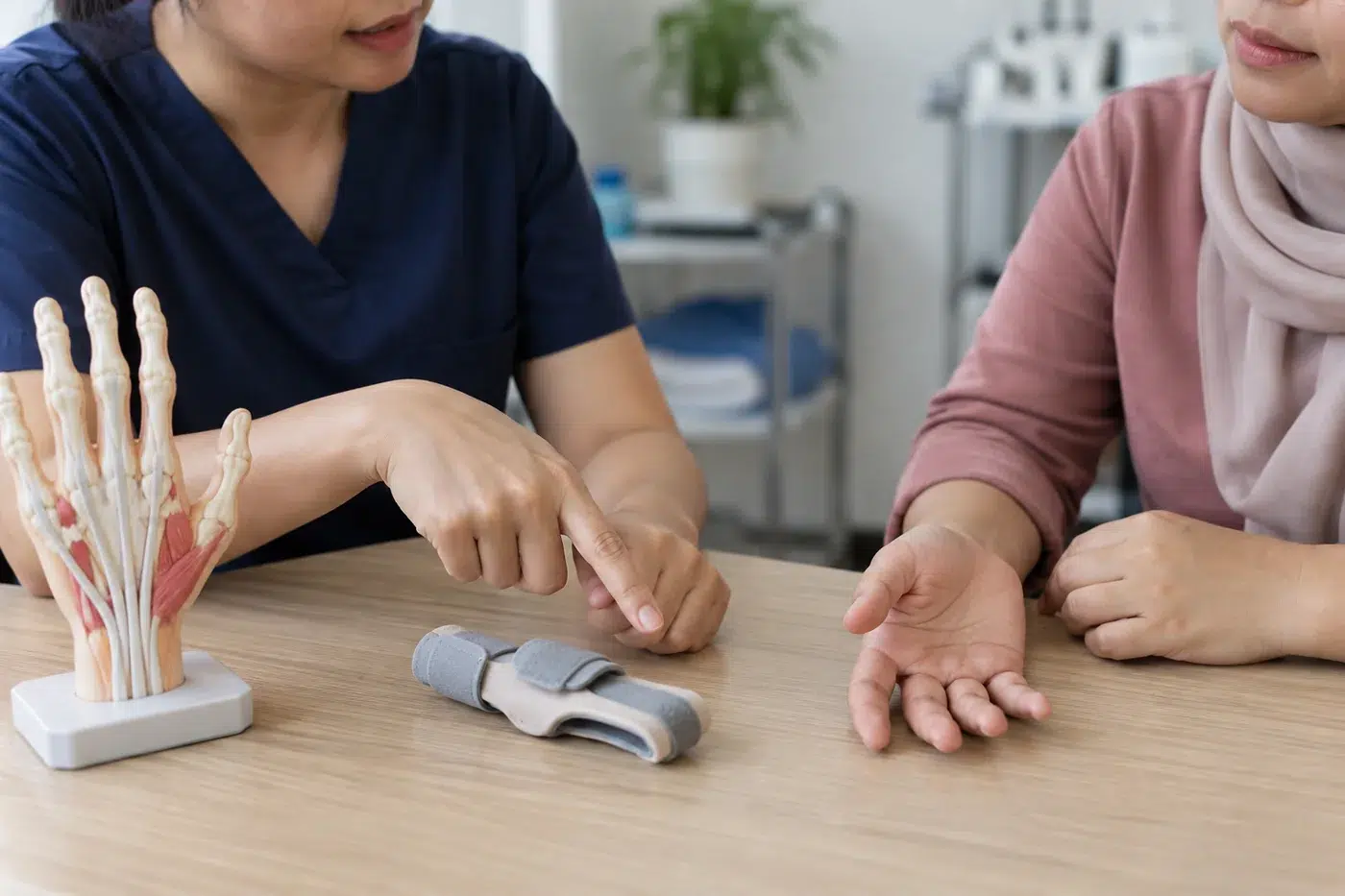 Trigger Finger 4 Female physiotherapist explaining a finger support beside a hand anatomy model